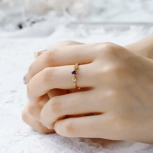 Détail d'une bague en argent 925 doré avec grès bleu et topaze sur dentelle blanche