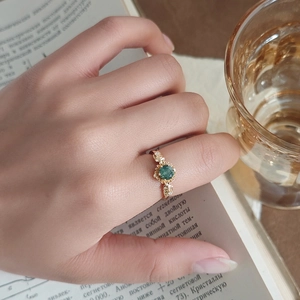 Detail of sunflower ring with green agate stone and leaf carvings on silver band