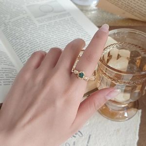 Detail of sunflower ring with green moss agate and gold leaf band on a finger