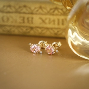 Detailed close-up of pink gemstone stud earrings with gold finish and vintage accents