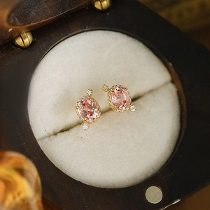 Macro shot of pink gemstone earrings with gold twisted edge in a vintage jewelry box
