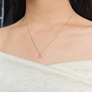 Close-up of pink gemstone pendant necklace worn by a model over a beige knit sweater