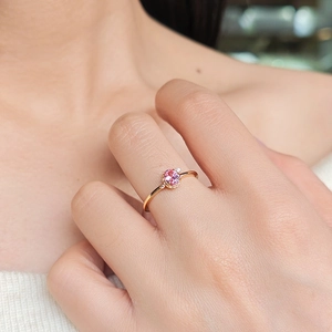 Close-up of pink gemstone ring featuring oval cut sapphire on elegant model hand