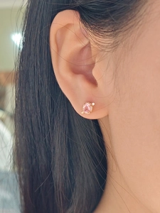 Detailed close-up of pink gemstone stud earrings with diamond accent in gold setting