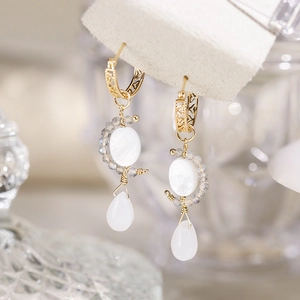 Détail macro de boucles d'oreilles dorées avec pierre de lune et motifs filigranes