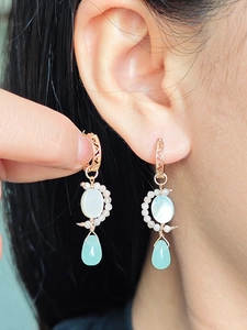Gros plan de boucles d'oreilles bohèmes avec nacre blanche et pierres bleues en goutte
