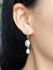 Détail d'une boucle d'oreille en argent plaqué or avec pendentif en nacre en forme de lune
