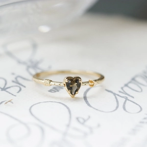 Macro view of heart-shaped smoky quartz ring with golden arrow design and polished finish