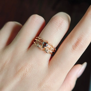 Close-up of three stacked rose gold rings featuring a heart gemstone and angel wings