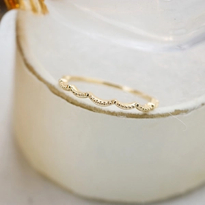 Macro shot of gold wave ring band with milgrain beaded edge details for stacking