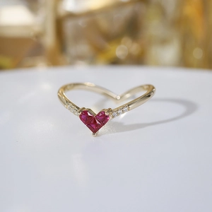 Macro detail of V-shaped gold ring featuring a heart-shaped ruby and diamond accents
