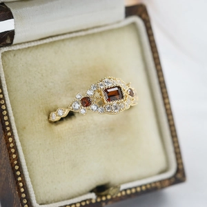 Makro-Detail des Granat-Ringes mit Diamanten in einer Vintage-Samt-Schmuckschatulle