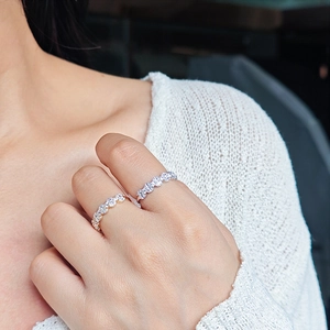Détail de bagues empilables en zircon plaqué or et argent portées avec un pull en maille