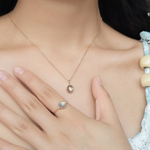 Detalle de anillo de cadena ajustable con cuarzo ahumado y set de collar dorado
