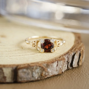 Macro-opname van S925 vergulde granaatring met filigraan holle details op houtvlak