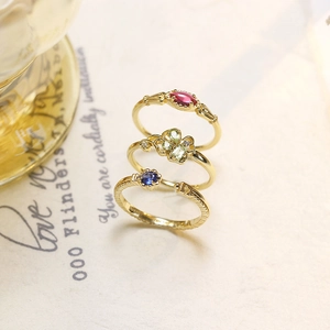 Macro-detail van drie vintage gouden ringen met rode, groene en blauwe edelstenen op papier