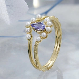 Gros plan d'une bague S925 dorée avec tanzanite en poire et perles blanches