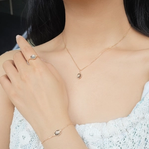 Detalle de conjunto de joyas doradas con cuarzo ahumado en la piel de modelo