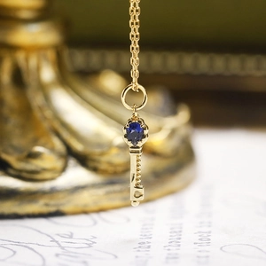 Macro-opname van de gouden sleutelhanger met een centraal geplaatste blauwe saffier