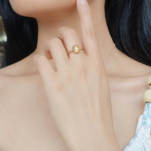 Detail of S925 silver gold-plated ring featuring an oval amber stone on model's hand