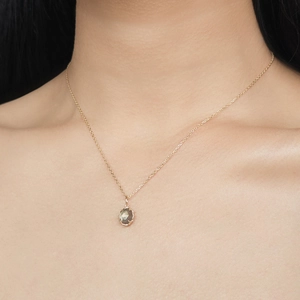 Primer plano de collar dorado con colgante ovalado de cuarzo ahumado en el cuello