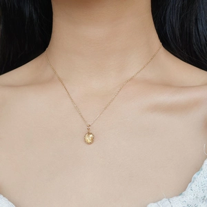 Close-up of a model wearing an S925 gold plated necklace with oval yellow crystal pendant