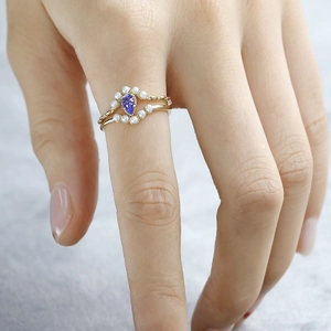 Vue macro d'un ensemble de bagues en or 14k avec tanzanite poire et perles
