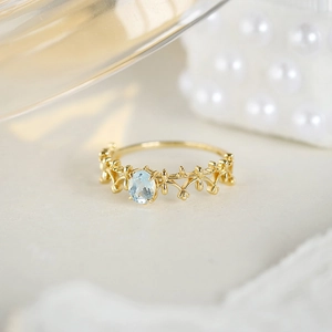 Macro shot of 14k gold plated lace ring with oval blue gemstone and crown detail