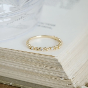 Detailed view of lace-style 14k gold plated silver ring with zircon on vintage book