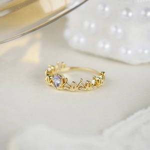 Macro view of crown lace ring in gold with heart-cut purple gemstone on marble