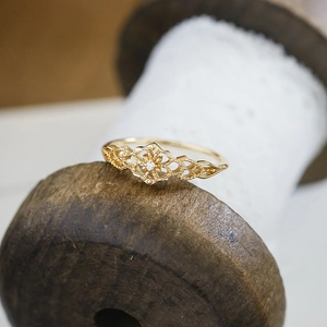 Makroaufnahme des 14k vergoldeten Spitzenrings mit Zirkon auf einer Holzspule