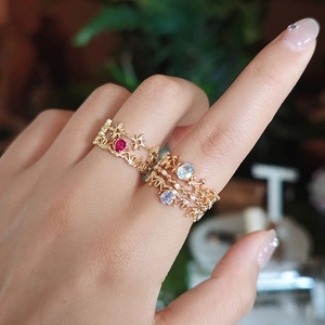 Detailed view of layered 14k gold rings featuring red, blue, and purple gemstones