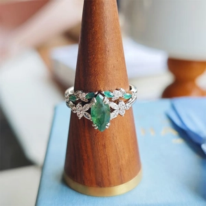 Macro detail of silver ring set with marquise-cut emerald green and white gemstones