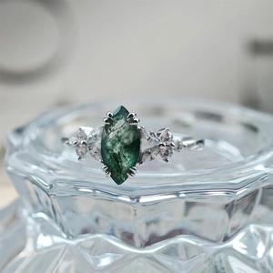 Macro shot of marquise-cut moss agate ring with silver floral setting and clear side stones