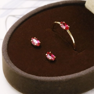 Detailed close-up of red marquise-cut corundum earrings and ring set in a velvet box