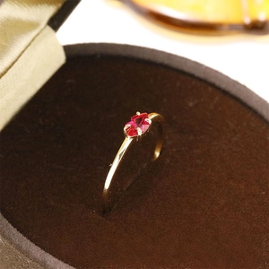 Close-up of a marquise-cut red gemstone gold ring set in a luxury velvet jewelry box