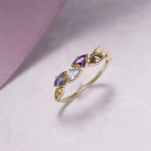 Macro shot of kite-cut gemstones on gold-plated ring with elegant milgrain side details
