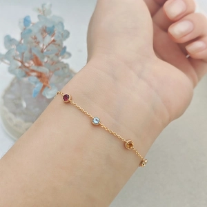 Bracelet élégant en chaîne dorée avec trois pierres précieuses rondes serties clos
