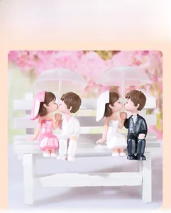 Close-up of PVC wedding couple figurines sitting on a miniature bench with umbrellas