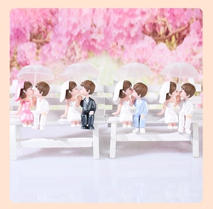 Detailed view of four miniature PVC couple figurines with pink umbrellas for wedding decor