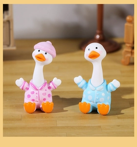 Pair of cute pink and blue polka dot duck figurines displayed on a wooden surface
