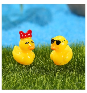 Gros plan de figurines de canards miniatures en résine jaune sur de l'herbe synthétique