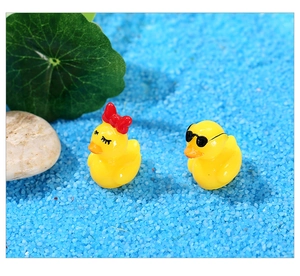 Gros plan de canards miniatures avec nœud et lunettes de soleil sur sable bleu