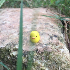 Miniature yellow resin duck figurine on mossy rock for bonsai micro landscape decor