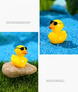 Detail view of yellow resin duck figurine with sunglasses on a micro landscape base