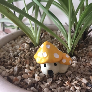 Macro detail of yellow mushroom house miniature decor set in garden pebbles