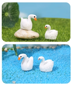 Detail of miniature resin swans on green grass and blue sand for micro landscape