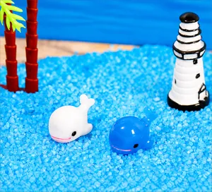 Détail de figurines dauphins en résine bleu et blanc dans un micro paysage de plage
