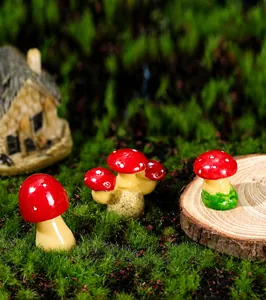 Detailed view of three miniature red resin mushrooms on moss for fairy garden decor