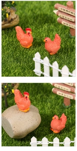 Detailed view of miniature resin rooster and hen figurines in a garden landscape scene